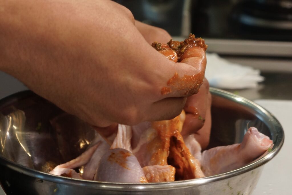 ミックススパイスに塩、オリーブ油を入れて混ぜたペーストを丸鶏に塗り塗りしていきます。